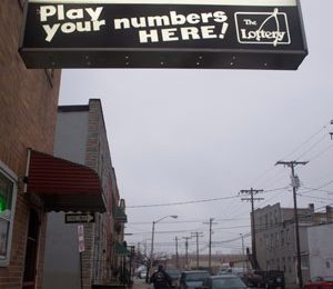 A sign for Locust Point Tavern, a neighborhood bar, glows against a gray sky. By Nahal Mottaghian/Capital News Service
