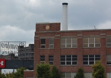 The Under Armour logo hangs on an overpass near the company’s Locust Point complex, in front of the Domino Sugar factory's famous sign. By Kate Yoon/Capital News Service