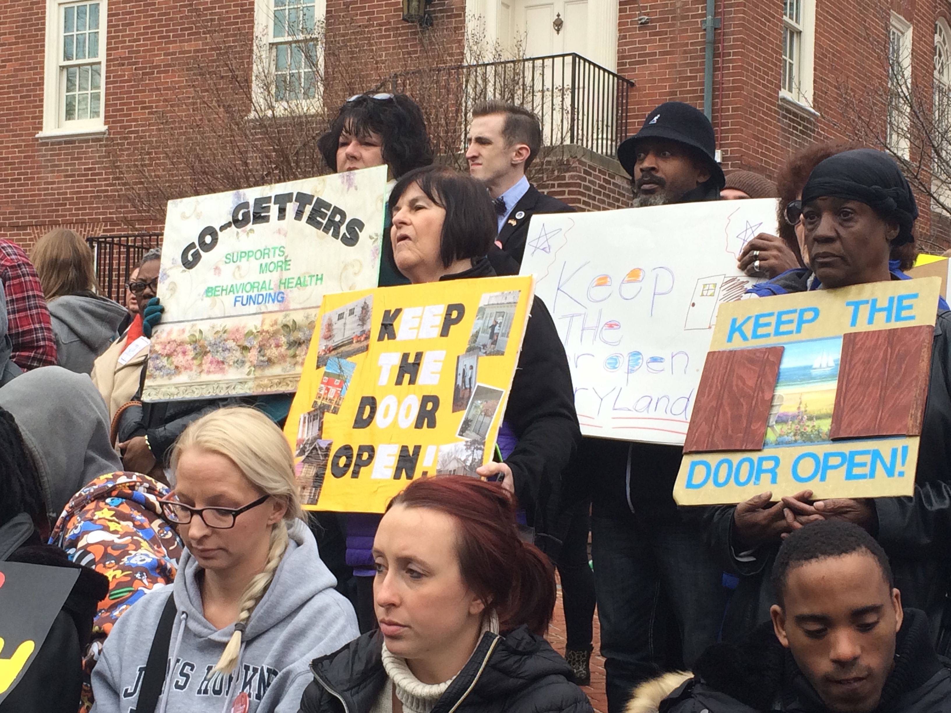 Ralliers hold signs showing support for the Keep The Door Open Act, which would require the state to increase funding for behavioral health care yearly with the rate of inflation, in Annapolis on Thursday, February 25, 2016. (Capital News Service photo by Leo Traub)