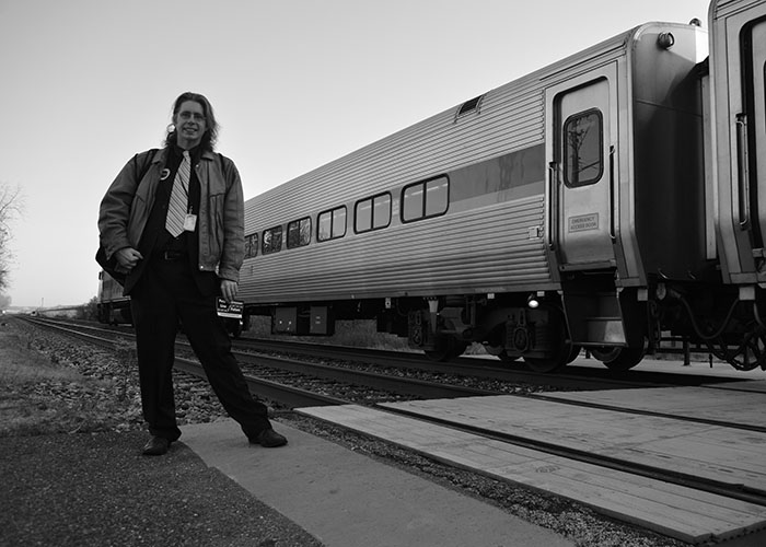 Gregory Sanders is a long time public transit advocate and the vice president of the Purple Line Now coalition. Here, he stands in front of a MARC train at the College Park Metro station, which he takes every day from his home in Ellicott City. His father, Harry Sanders, first proposed the Purple Line. (2015 Capital News Service photo by Brittany Britto)