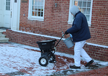 A state employee covers the sidewalks with ice melt pellets on January 21, 2016, right outside of the Maryland State House in Annapolis, Maryland, in preparation for Friday’s anticipated snow storm. (Capital News Service photo by Josh Magness.)