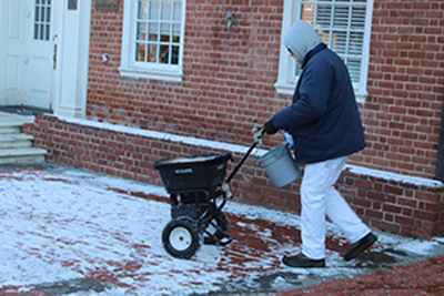 A state employee covers the sidewalks with ice melt pellets on January 21, 2016, right outside of the Maryland State House in Annapolis, Maryland, in preparation for Friday’s anticipated snow storm. (Capital News Service photo by Josh Magness.)