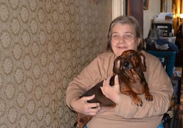 Dawn Ford sits in a first-floor hallway with her dog, Sarge, who catches the mice that come into her South Smallwood Street home. (Capital News Service photo by Abby Mergenmeier)