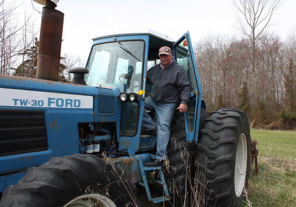 Wilbur Levengood, a Caroline County Commissioner, stands on one of his tractors on his land nears Goldsboro, Md. (Photo by J.F. Meils/Capital News Service)