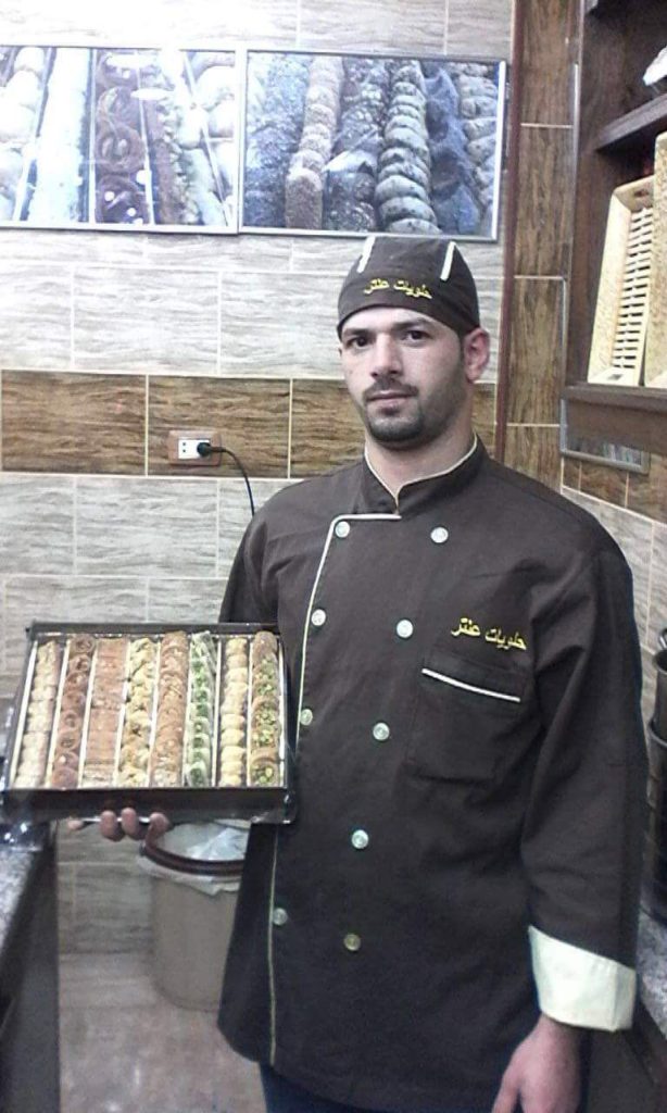 Nour at his dessert shop in Jordan. He is holding a box of baklava. (Photo courtesy of Nour).