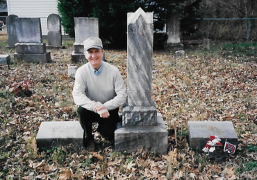 LTC John P. Zebelean III (ret.) posing next to the grave of relative Private Matthew J. Ham, 2nd Regiment, North Carolina Junior Reserves (1861-1865). The plot is located on his family’s former property in Wayne County, NC. Zebelean’s ancestors and five of their slaves are buried here. Photo Courtesy LTC John P. Zebelean III.