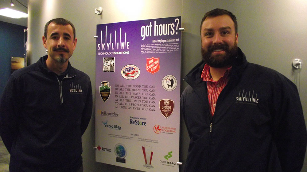 Skyline2 – Jason Ross, the vice president, and Nick Caleo, a CAD engineer, pose with a plaque in their office that reminds and inspires employees to volunteer in the community. (Savannah Williams/Capital News Service)