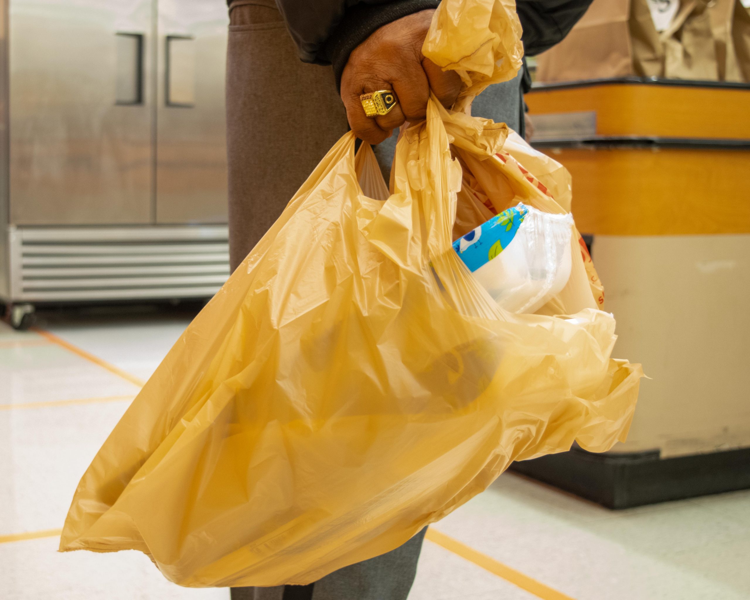 A man holding a plastic carryout bag.