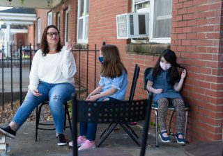Margaret Szabo, 42, sits with her two daughters on the porch of their home in Richmond, Virginia, on Nov. 6. The Richmond Redevelopment and Housing Authority, which owns Szabo’s home, filed an eviction case against her for unpaid rent last fall. She said an aid organization paid the back rent, but she’s behind again in 2020. (Nick McMillan/Howard Center)