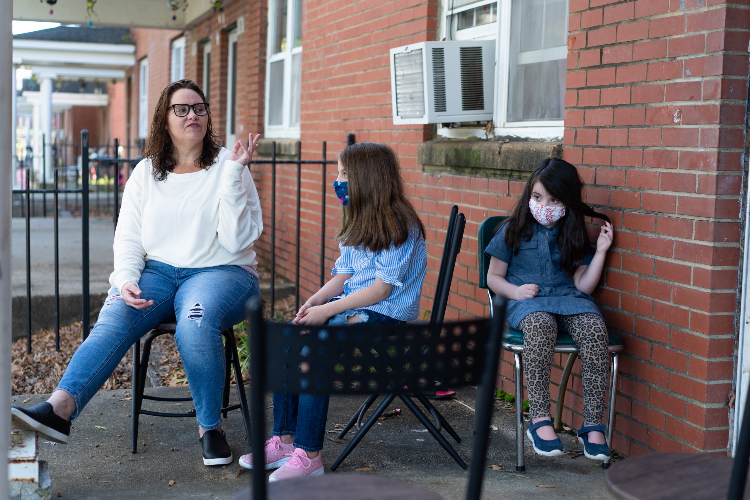 Margaret Szabo, 42, sits with her two daughters on the porch of their home in Richmond, Virginia, on Nov. 6. The Richmond Redevelopment and Housing Authority, which owns Szabo’s home, filed an eviction case against her for unpaid rent last fall. She said an aid organization paid the back rent, but she’s behind again in 2020. (Nick McMillan/Howard Center)