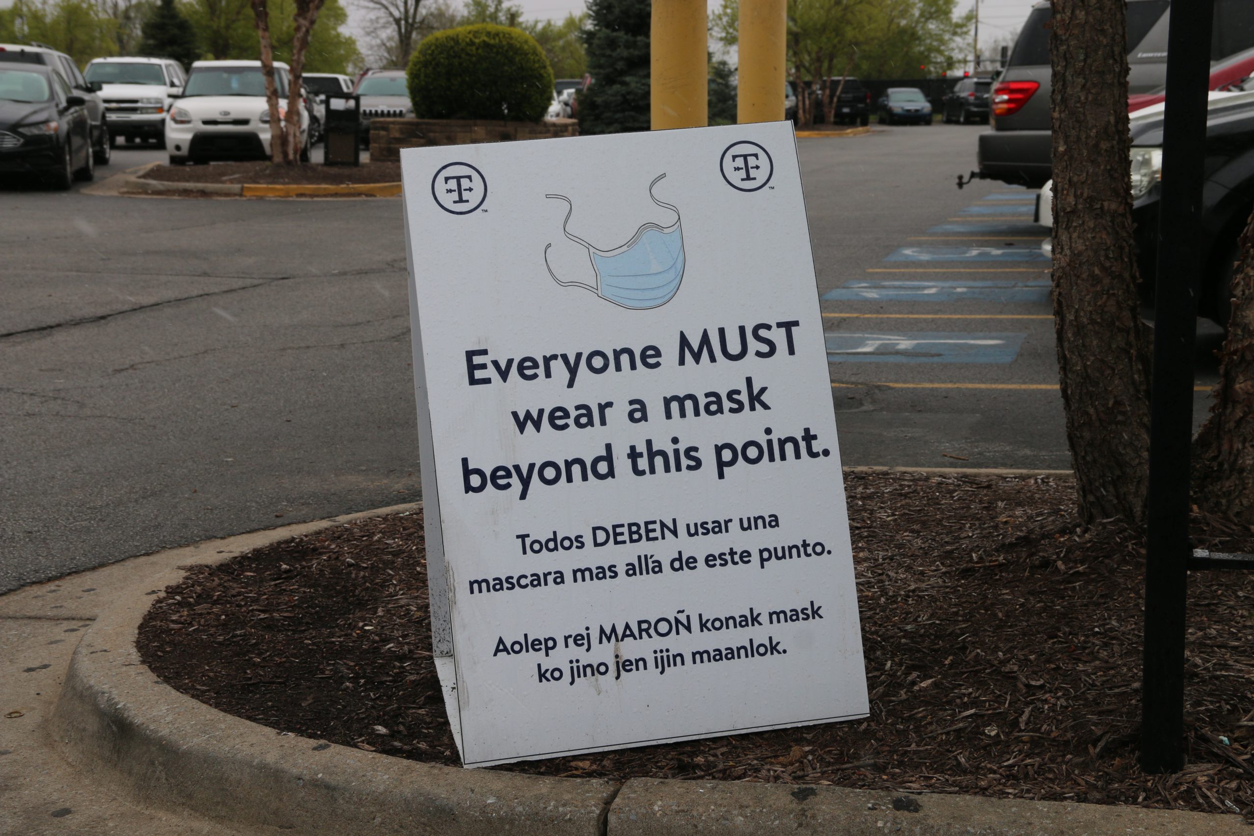 Outside of the Tyson Berry Street plant in Springdale, Arkansas, a sign in English, Spanish, and Marshallese stands reminding employees to wear a mask before entering the location, April 20, 2021. Tyson currently provides surgical-style face masks to its employees. (Photo by Abby Zimmardi)