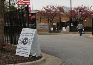 A Tyson employee walks into the team member entrance at the Berry Street location in Springdale, Arkansas, on April 20, 2021. A sign in their path read “Social Distancing Required at all Times” written in English, Spanish and Marshallese. (Photo by Mary Hennigan)