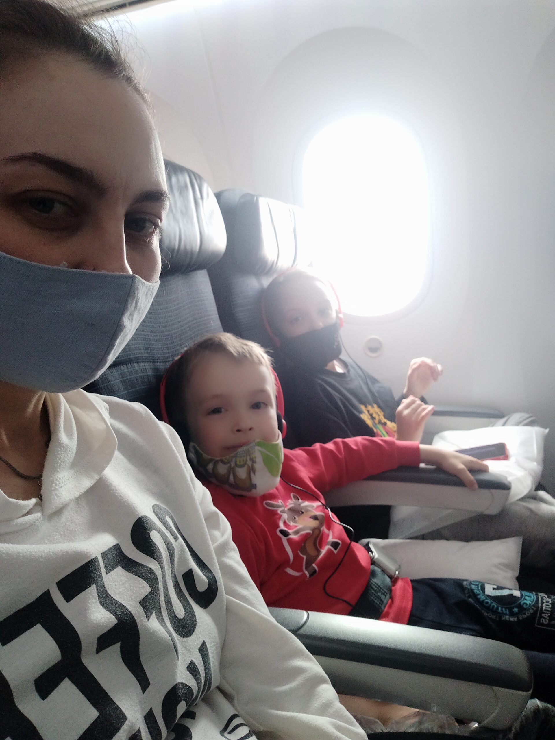 A woman sits with her two children on a plane.