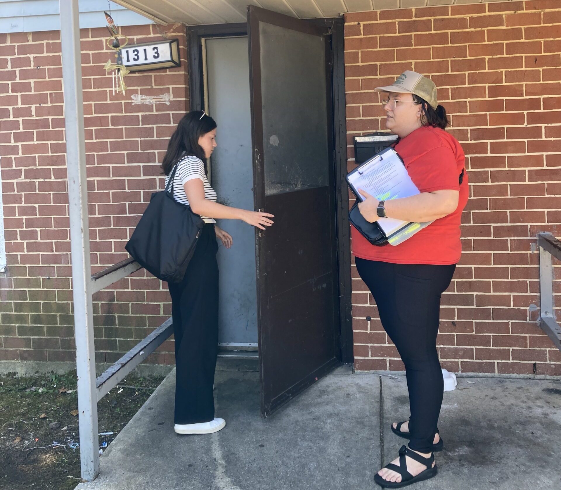 Two legal aid workers knock on a renter's door to distribute fliers.