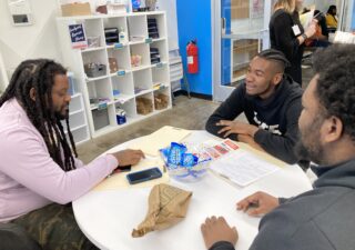Three men sit around a table at an expungement clinic in Baltimore.