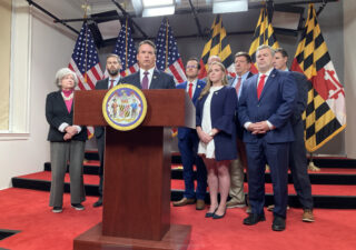Members of the Maryland Joint Republican Caucus gather around a podium to announce their 2024 public safety agenda against a backdrop of Maryland and U.S. flags.