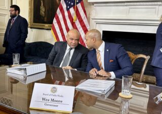 State Treasurer Dereck Davis (left) and Gov. Wes Moore (right) convene after a meeting of the Board of Public Works on Jan. 31, 2024, where each addressed news reports about a sale of the Baltimore Orioles. (Sapna Bansil/Capital News Service)