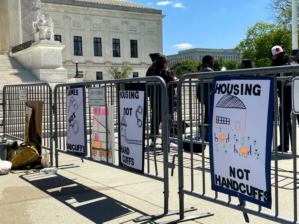 Signs outside the Supreme Court demand housing instead of criminalization of homelessness.