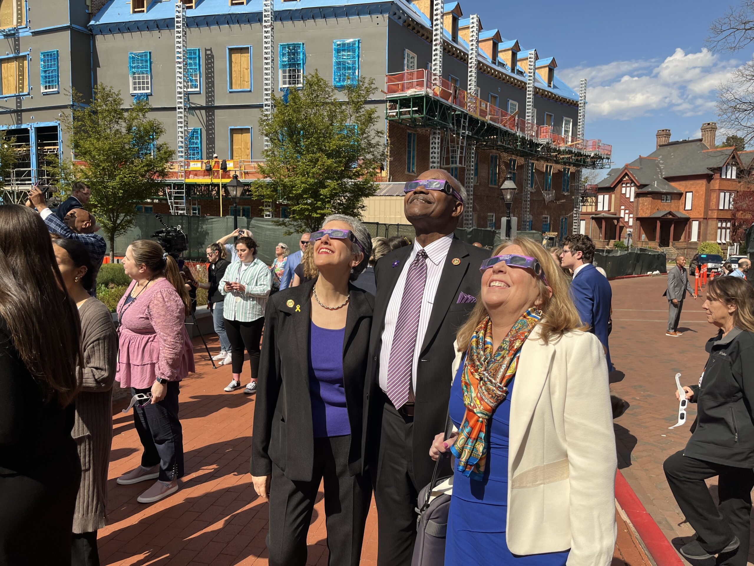Sen. Cheryl Kagan, D-Montgomery, Sen. Benjamin Brooks, D-Baltimore, and Sen. Mary Beth Carozza, R-Somerset, Wicomico and Worcester, are wearing eclipse glasses and staring at the sky smiling outside of the Maryland State House.