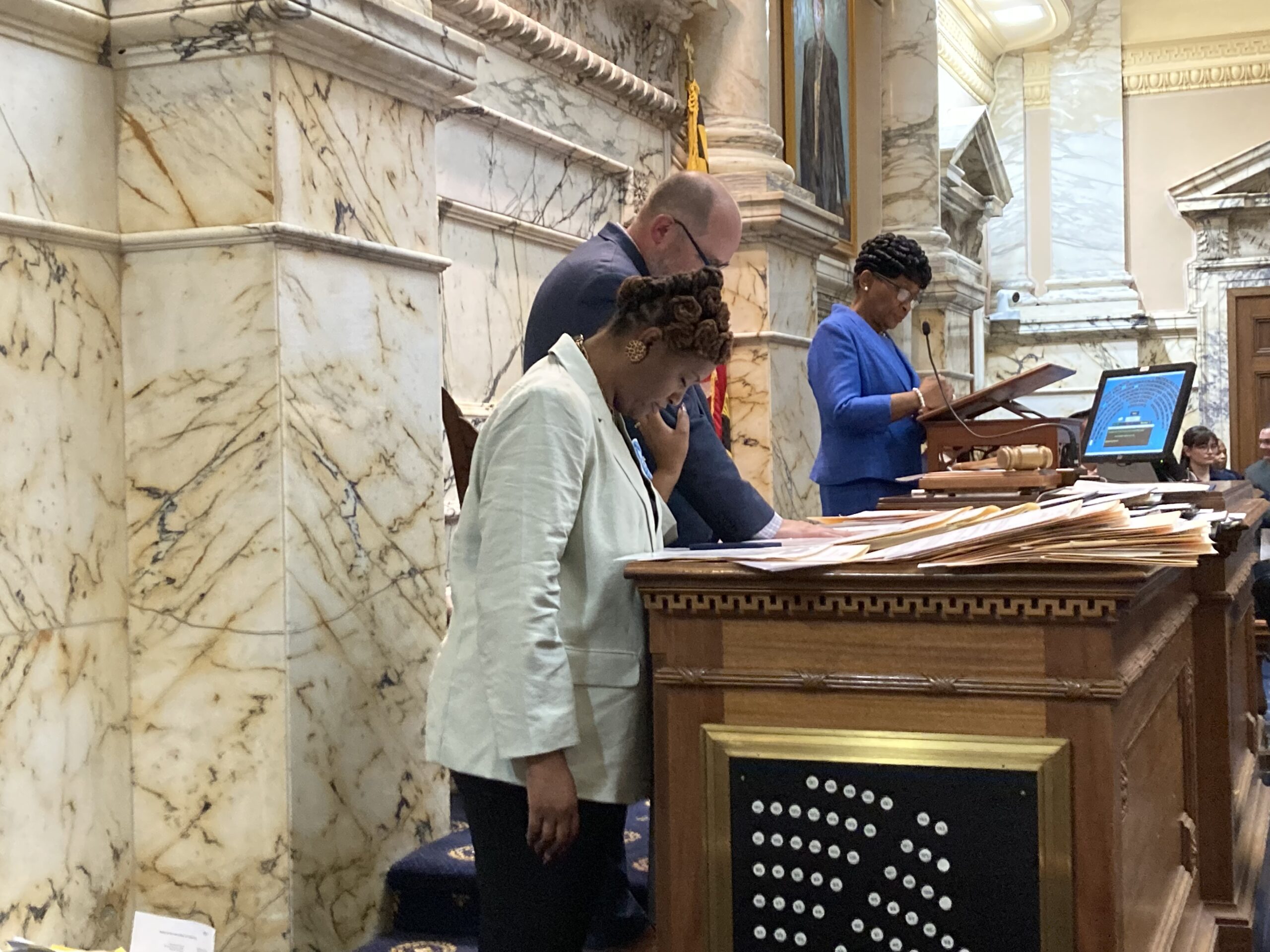 Del. Stephanie Smith, D-Baltimore City, and Jeremy Marcus, chief of staff for House Speaker Adrienne Jones, D-Baltimore, bow their heads during the prayer opening the chamber's afternoon session.