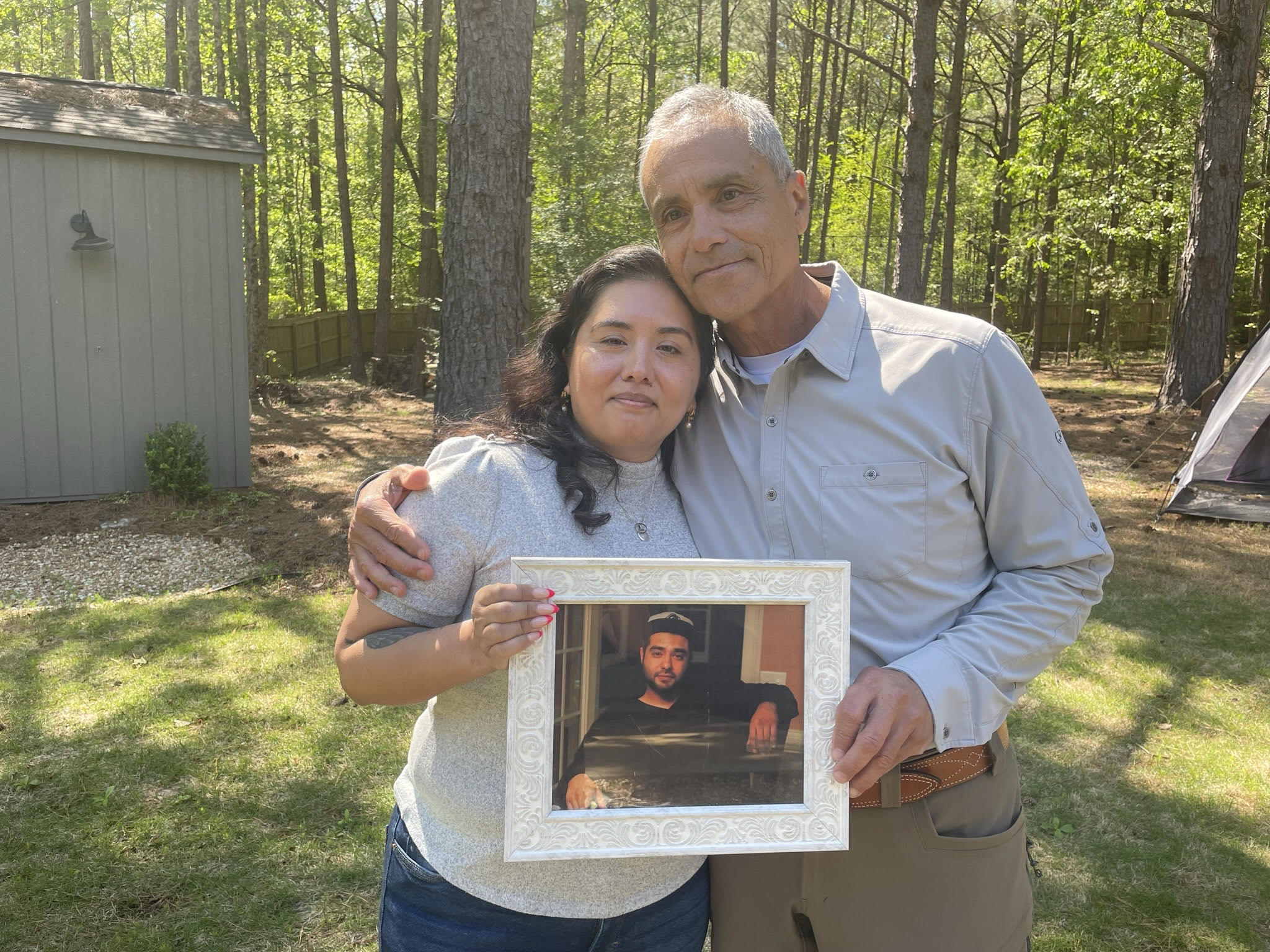 Patricia Ragan and her father, Rodrigo Arreola, hold a photo of her brother, Hector Arreola, outside of Rodrigo Arreola's home on April 11, 2023, in Columbus, Ga. The cause of Hector Arreola's death was changed from an accident to homicide caused by "sudden cardiac death following struggle with law enforcement including prone position restraint complicating acute methamphetamine toxicity.'' In 2021, his family was awarded $500,000 in damages in a settlement with the city of Columbus. (Eve Sampson/Howard Center for Investigative Journalism via AP)