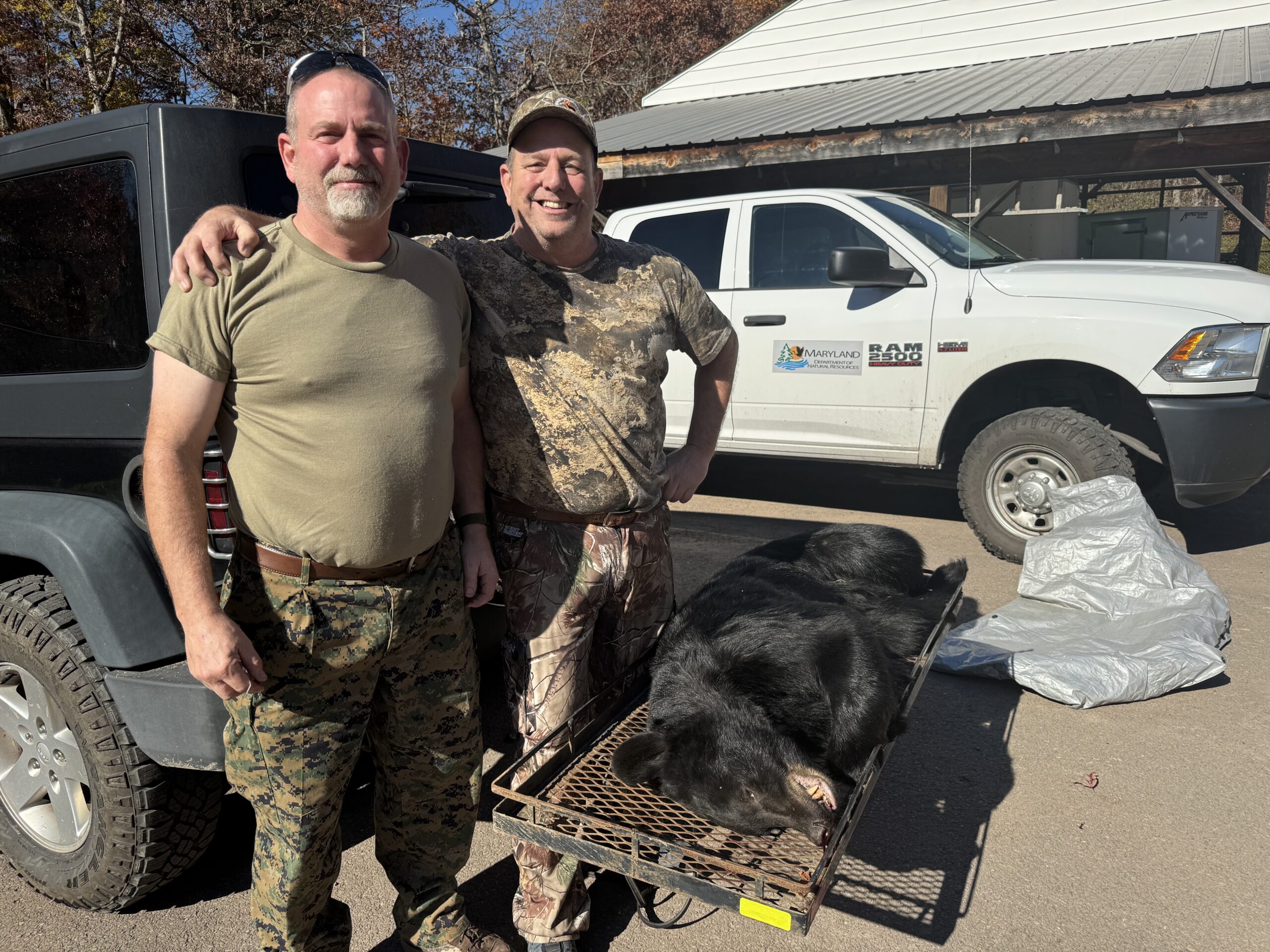 Two hunters stand over a black bear.