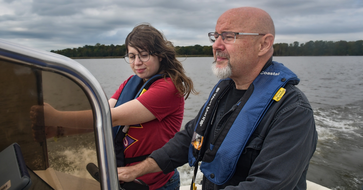 Theaux Le Gardeur and Andrea Rudai are on a motorboat on the Gunpowder River on an overcast day. Le Gardeur is at the helm.