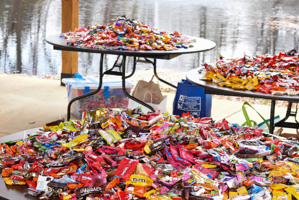 Piles of halloween candy sit atop tables.