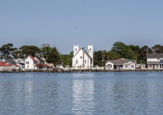 A white church surrounded by homes on the waterfront