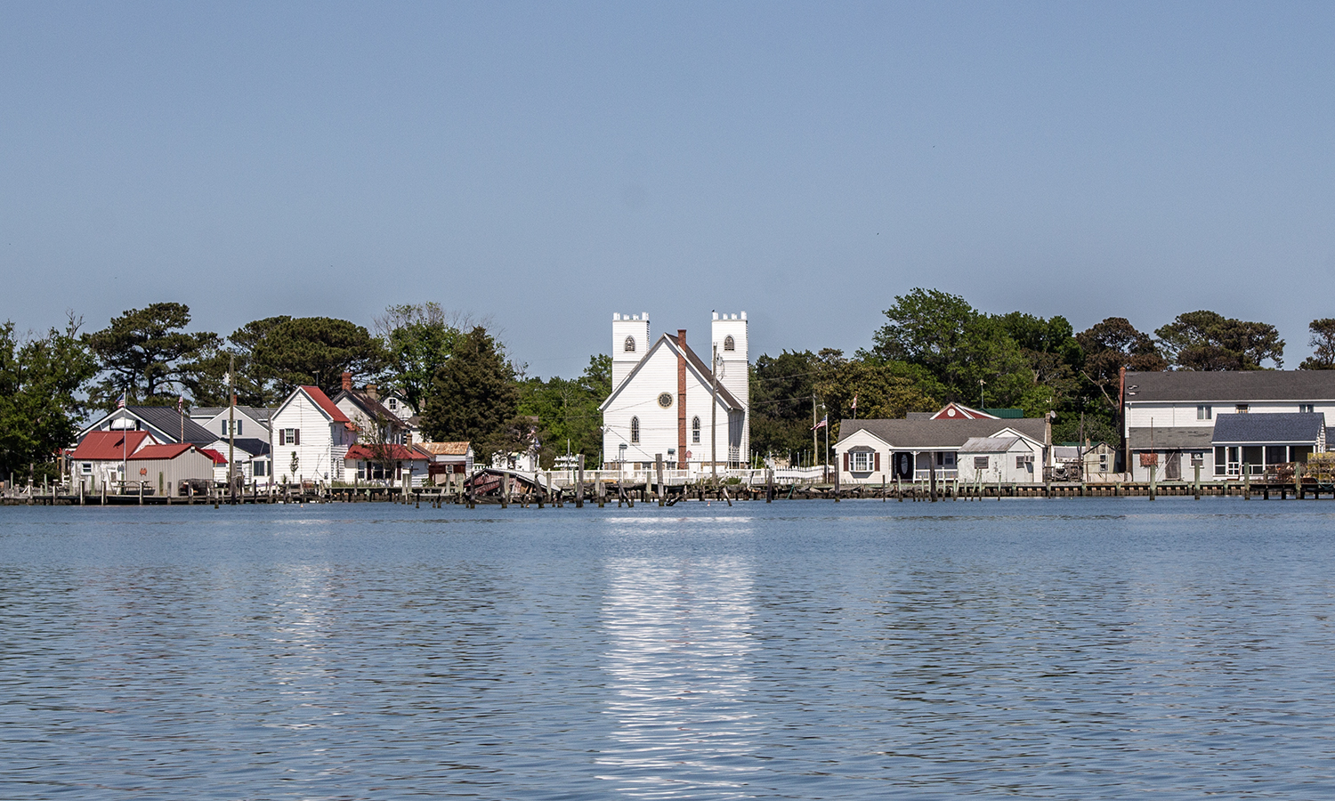 A white church surrounded by homes on the waterfront