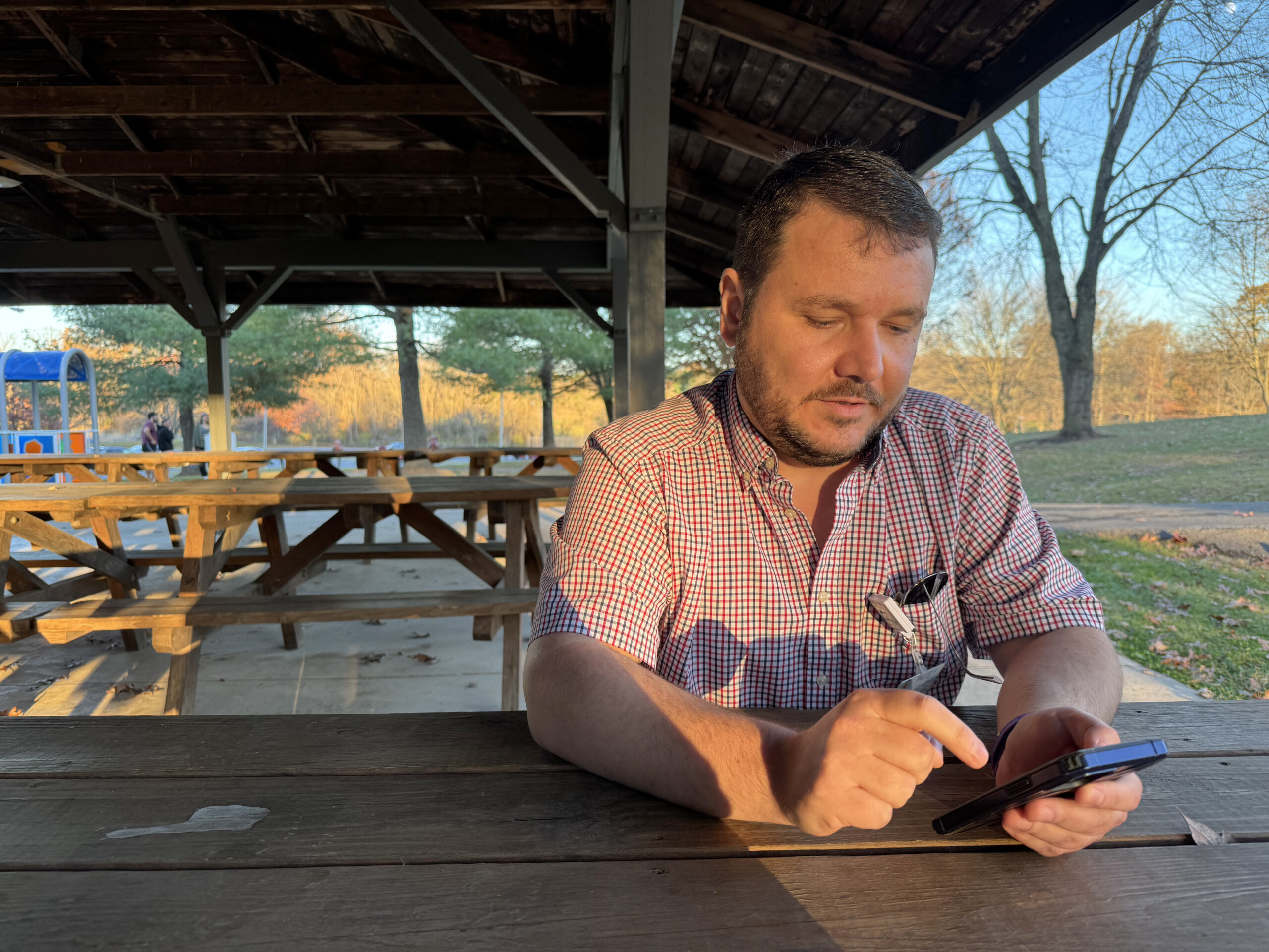 A man scrolls through his phone in the park.