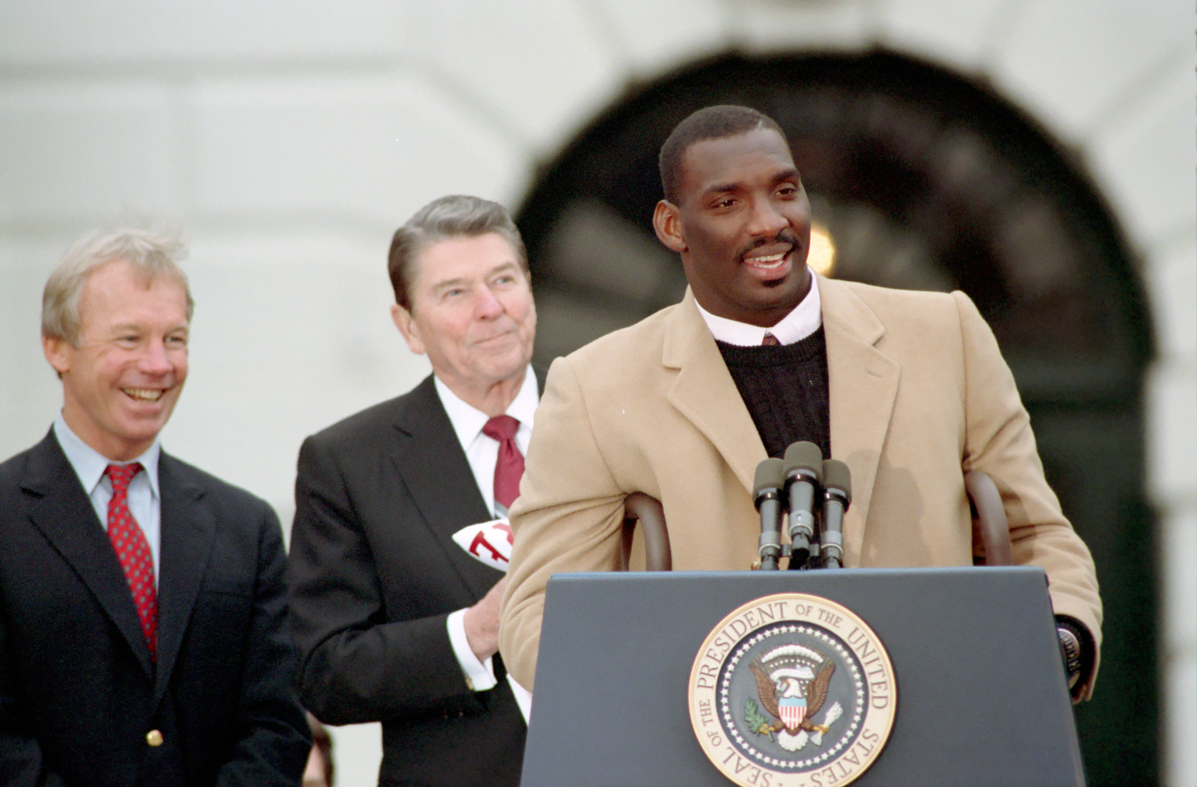 As President Ronald Reagan looks on, Doug Williams speaks at a 1988 ceremony to congratulate the Super Bowl XXII winners, the Washington Redskins, on the south lawn of the White House.
