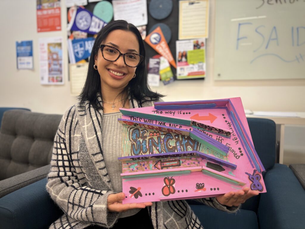 Lissa Bautista, a Raw Art Works alumna, poses for a portrait while holding the maze she created. (Tolu Talabi/Capital News Service)